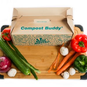 some vegetables on a cutting board by a compost buddy box, a disposable compost bin liner