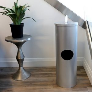 a silver floor wipes dispenser with trash can by a set of stars and a plan on a table