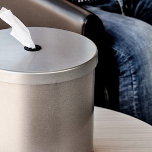 a cleanli wipes dispenser on a table by a chair with a person sitting