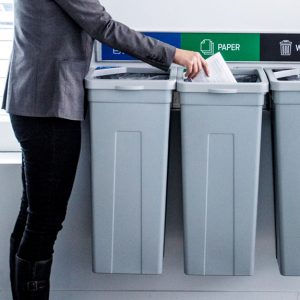 a man putting garbage in the rise series wall mounted commercial indoor recycling waste bins