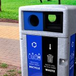 an outdoor recycling station by walkway in park