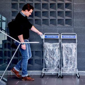 a man throwing personal protective equipment in a ppe disposal bin system